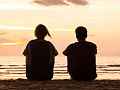 two people sitting by the ocean